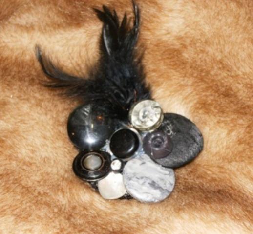 Spilla con piume nere e vecchi bottoni